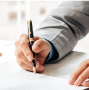 契約書にペンで署名している人物の画像